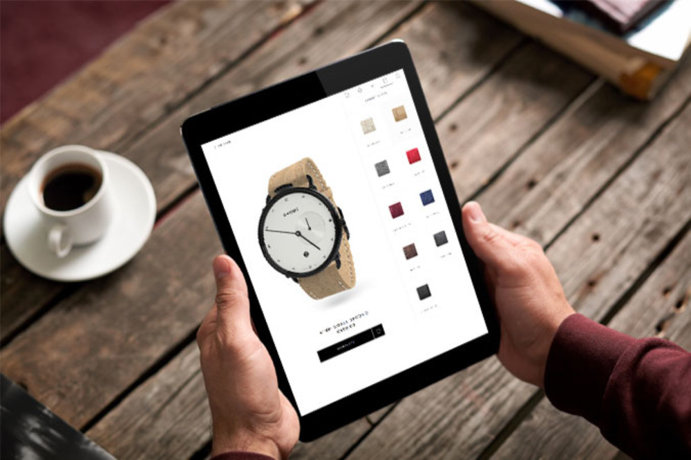 webshop design: Man holding a tablet with a watch customization page on the screen
