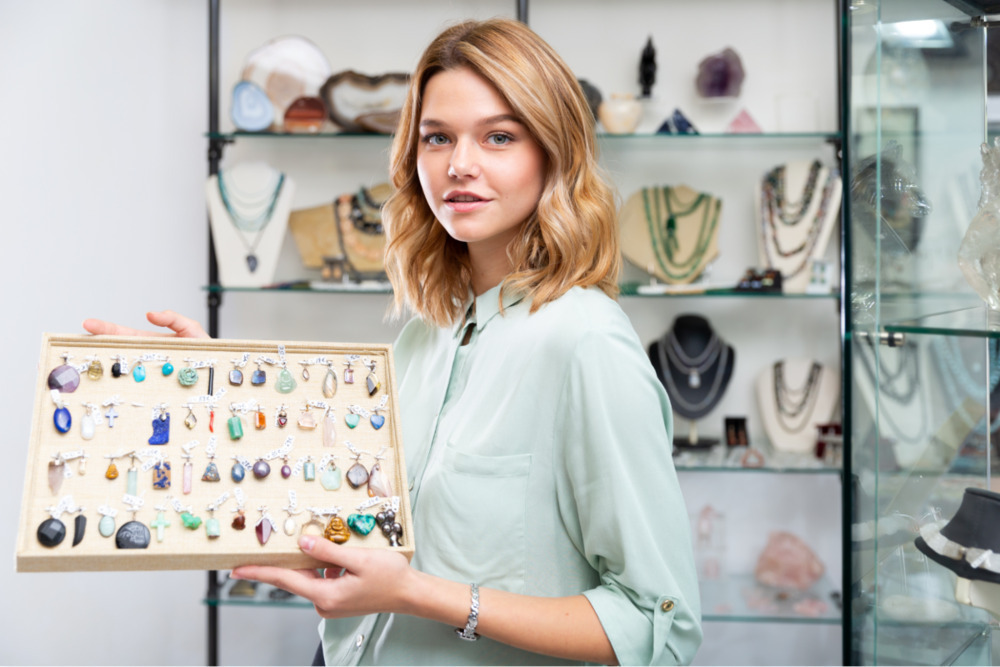 print-on-demand jewelry: Woman holding up a display board with various pendants